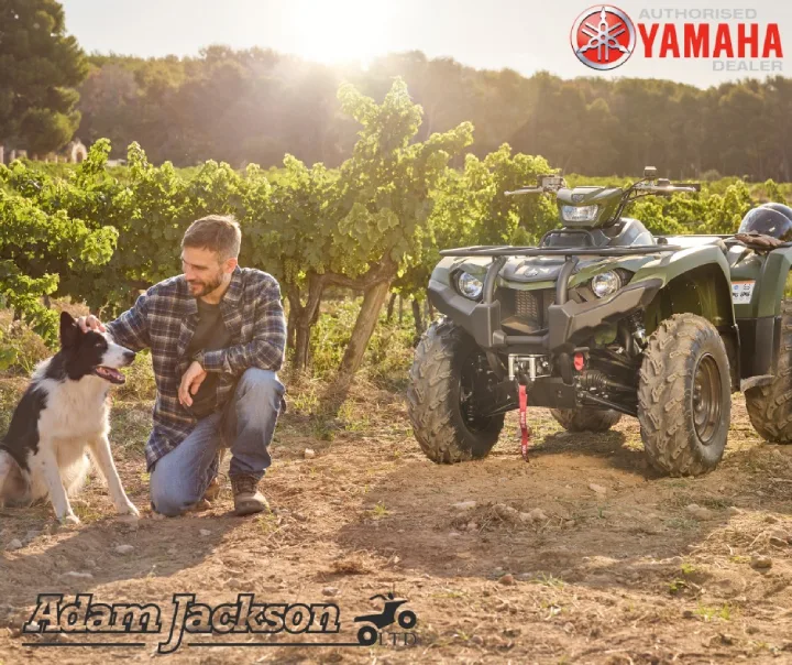 Man with dog next to Yamaha ATV in vineyard