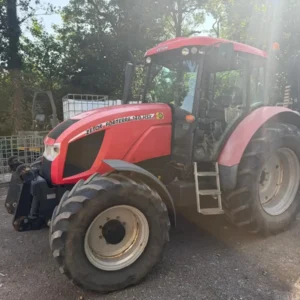 Red Zetor tractor with cab and front linkage in a farmyard